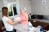 cheerful young girl ironing and helping elderly woman at home
