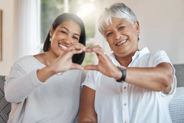 Two women bring their hands together to form a heart shape, signifying the importance of maintaining a healthy heart.