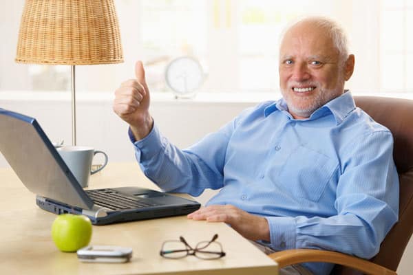 An older man wonders, “What is Parkinson’s disease?” at laptop.